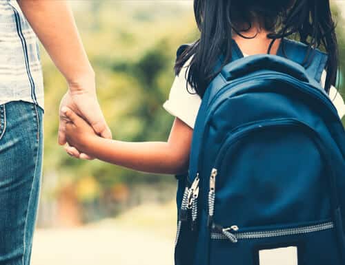 Man holding child's hand to school.